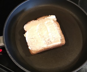 フライパンの上に乗せたマヨネーズを塗った雑穀食パンの画像