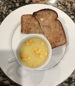 半分に切ったグリルドチーズサンドイッチとコーンスープの画像