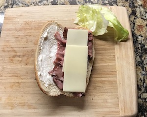 開いたコッペパンにスライスしたローストビーフとスライスチーズを乗せている画像