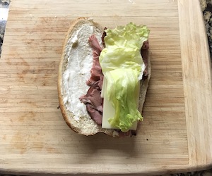 開いたコッペパンにスライスしたローストビーフとスライスチーズとレタスを乗せている画像