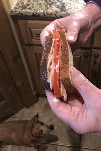 手で半分に折られたサンドイッチの画像