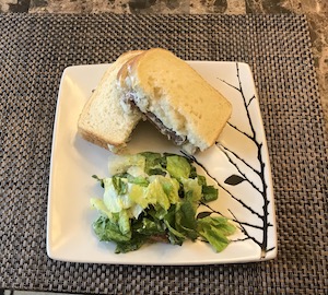 半分に切ったステーキサンドイッチとサラダがお皿に乗っている画像