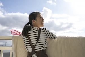 天気の良い日に布団を干していながら横を向いて笑っている画像