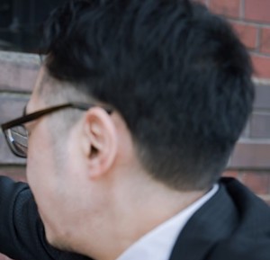 メガネをかけたツーブロックの男性の横顔を後ろから写している画像