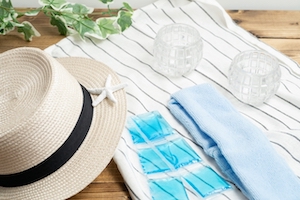 洋服の上に帽子やタオル、保冷剤を置き夏のお出掛け用の着替えを用意している画像