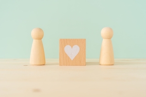 積み木の男女がハートの形をしたブロックを挟んで立っている画像