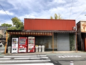 シャッターが閉まっている昔ながらのお店の前にある自動販売機が写っている画像