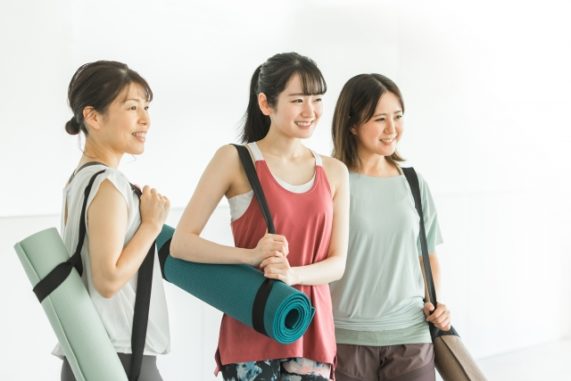 ジムでヨガマットを持った3人の女性達